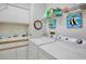 Functional laundry room with washer, dryer, sink, storage cabinets, and charming decor at 3412 E Chelmsford Ct # 42, Sarasota, FL 34235