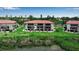 Exterior view of condos with red tile roofs, balconies, manicured lawns, and waterfront in the background at 3420 Wild Oak Bay Blvd # 120, Bradenton, FL 34210