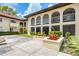 Beige condominium building with arched entryways, planter boxes of red flowers, and concrete walkways at 3690 Pinecrest St # 114, Sarasota, FL 34232