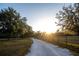 Scenic driveway leading to a charming home, lined with mature trees and a rustic wooden fence at 3717 Downer Ave, Sarasota, FL 34240