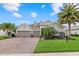 Charming single-story home featuring a three-car garage, well-manicured lawn, and lush landscaping with mature palm trees at 3808 Eastham Ln, Bradenton, FL 34211