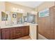 Spacious bathroom featuring a double vanity with dark wood cabinets, a glass enclosed shower, and neutral-toned tile flooring at 4016 Azurite Way, Bradenton, FL 34211