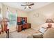 Bedroom with neutral walls, carpet and a ceiling fan, includes a desk area and a comfortable couch at 4016 Azurite Way, Bradenton, FL 34211