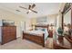 This bedroom features a wooden bed frame, an area rug, a ceiling fan, a dresser, and natural light streaming in through the windows at 4016 Azurite Way, Bradenton, FL 34211