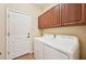Functional laundry room boasts a side-by-side washer and dryer, ample overhead cabinet storage, and a convenient access door at 4016 Azurite Way, Bradenton, FL 34211