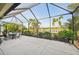 Enjoy outdoor living on the screened patio with a lake view, dining table, umbrella, lush landscape and tranquil surroundings at 4016 Azurite Way, Bradenton, FL 34211