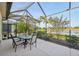 Enjoy outdoor living on the screened patio with a lake view, dining table, umbrella, and tranquil surroundings at 4016 Azurite Way, Bradenton, FL 34211