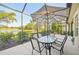 Enjoy outdoor living on the screened patio with a lake view, dining table, umbrella, and tranquil surroundings at 4016 Azurite Way, Bradenton, FL 34211