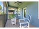 Screened in porch with two blue striped chairs and a small table at 4548 Chinkapin Dr, Sarasota, FL 34232