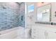 Stylish bathroom featuring blue tiled walls, a soaking tub, and a modern vanity with a rectangular mirror at 4815 W Sunset Blvd, Tampa, FL 33629