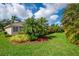 Beautifully landscaped backyard featuring lush green grass, palm trees and tropical foliage at 4912 Sabal Lake Cir, Sarasota, FL 34238
