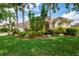 Charming single-story home featuring lush tropical landscaping, a barrel tile roof, and a front-entry two-car garage at 4912 Sabal Lake Cir, Sarasota, FL 34238