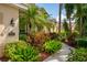 Landscaped front yard featuring vibrant flowers, tropical foliage, a sidewalk, and a view of the home's facade at 4912 Sabal Lake Cir, Sarasota, FL 34238