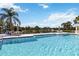 Community pool surrounded by palm trees, lounge chairs, and views of a serene pond at 5227 Aqua Breeze Dr, Bradenton, FL 34208