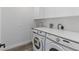 Well-lit laundry room with white washer and dryer, countertop, and upper cabinets at 532 Yale Rd, Venice, FL 34293
