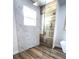 Modern shower with wood accent wall, marble tile, glass partition, and a square rainfall showerhead at 532 Yale Rd, Venice, FL 34293