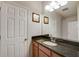 Bathroom featuring a dark granite countertop, wooden cabinets, and a large framed mirror at 6001 Anise Dr, Sarasota, FL 34238