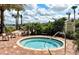 Community hot tub area surrounded by tall trees, chairs and a lake in the background at 6001 Anise Dr, Sarasota, FL 34238