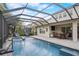 Screened-in pool with spa, lounge chairs, outdoor kitchen, and lush tropical landscaping at 6001 Anise Dr, Sarasota, FL 34238