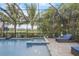 Screened in swimming pool and spa with lush landscaping and an outdoor basketball hoop at 6001 Anise Dr, Sarasota, FL 34238