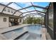 Home's screened-in pool area with a spa, outdoor dining, and an outdoor kitchen at 6001 Anise Dr, Sarasota, FL 34238