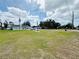 Expansive front yard with a lush green lawn featuring a driveway leading to a charming light blue home with inviting curb appeal at 612 Shore Rd, Nokomis, FL 34275