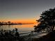 Picturesque sunset reflecting on calm water, framed by silhouetted trees and a distant pier at 612 Shore Rd, Nokomis, FL 34275