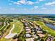 Expansive aerial view showcases real estate in a community with a golf course and lakes under a bright blue sky at 7582 Camden Harbour Dr, Bradenton, FL 34212
