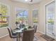 Cozy dining area with a glass table and seating for four, bathed in natural light from large windows at 7582 Camden Harbour Dr, Bradenton, FL 34212