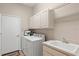 Bright laundry room with white cabinets, a washing machine, a dryer, and a utility sink at 7582 Camden Harbour Dr, Bradenton, FL 34212
