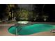 Inviting pool and hot tub area at night, illuminated with landscape lighting and surrounded by palm trees at 7582 Camden Harbour Dr, Bradenton, FL 34212