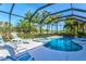 A covered pool and hot tub with patio furniture and lush landscaping create a private backyard oasis at 7582 Camden Harbour Dr, Bradenton, FL 34212