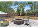 Backyard featuring a stone fire pit and seating surrounded by mature trees and a wooden fence at 815 Hand Ave, Sarasota, FL 34232