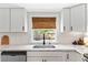 Bright, modern kitchen featuring white cabinets, marble countertops, stainless appliances, and woven window shades at 815 Hand Ave, Sarasota, FL 34232