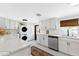 Stylish white kitchen with stainless steel appliances, white countertops, stackable washer/dryer, and decorative rug at 815 Hand Ave, Sarasota, FL 34232