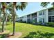 Exterior view of a well-maintained building with a lawn, palm trees, and a screened-in patio at 9470 High Gate Dr # 2213, Sarasota, FL 34238