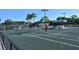 Active residents playing tennis on a well-maintained community court with palm tree accents in the background at 9470 High Gate Dr # 2213, Sarasota, FL 34238