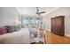 Bright main bedroom with wood floors, ceiling fan, and access to balcony with picturesque water views at 975 Whitakers Ln, Sarasota, FL 34236