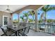 Covered outdoor patio with dining table overlooking serene water views and lush tropical landscape at 975 Whitakers Ln, Sarasota, FL 34236
