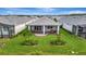 Aerial view of backyard featuring a covered patio, lush green lawn, and meticulous landscaping at 10394 Abaco Falls Dr, Englewood, FL 34223