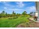 Spacious backyard featuring lush green grass, mature landscaping, and a glimpse of the screened-in patio at 10394 Abaco Falls Dr, Englewood, FL 34223