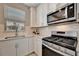 Close-up of kitchen sink and faucet with stainless steel appliances, including a microwave, and white cabinetry at 10394 Abaco Falls Dr, Englewood, FL 34223