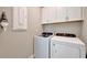 Bright laundry room equipped with a washer, dryer, and built-in cabinets at 10394 Abaco Falls Dr, Englewood, FL 34223