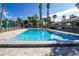 Community pool with lounge chairs, tables, and tropical landscaping on a sunny day at 1055 Beach Rd # B302, Sarasota, FL 34242