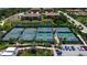 An aerial view of community tennis courts near a pond, parking lot and several residential homes in a Florida community at 12409 Osorio Ct # 102, Sarasota, FL 34238