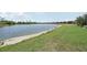 Scenic backyard lake view with lush green grass and homes in the distance on a sunny day at 13587 Vancanza Dr, Venice, FL 34293