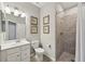 Well-lit bathroom with a tiled shower, neutral walls and stylish seashell decorative art at 13587 Vancanza Dr, Venice, FL 34293