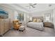 Beautiful bedroom with tufted headboard, tray ceiling, and a sitting area near a large window at 13587 Vancanza Dr, Venice, FL 34293