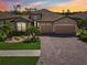 Attractive home exterior boasts a spacious garage, a brick driveway, lush landscaping, and a tile roof at 13587 Vancanza Dr, Venice, FL 34293