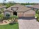 Beautiful home with three-car garage and tile roof, complemented by a lush landscaped yard and paver driveway, shows pride of ownership at 13587 Vancanza Dr, Venice, FL 34293